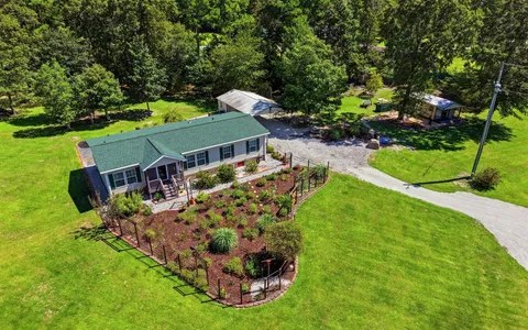 223 Blue Top Road, Jacksonville, from above: green-roofed home on a wide lawn with a fenced garden